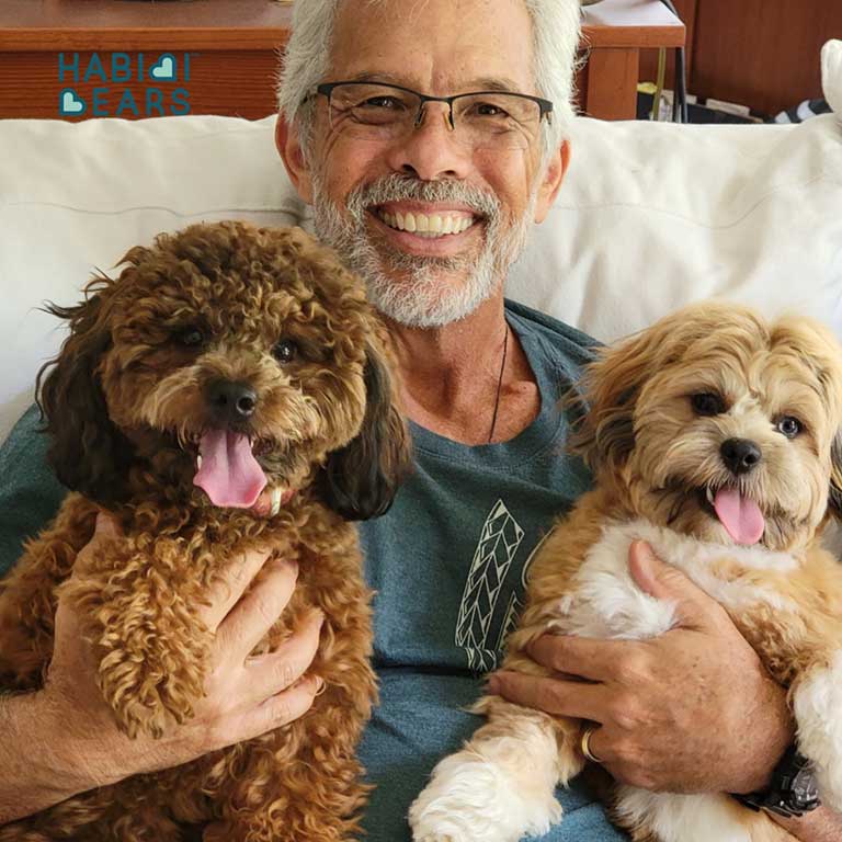Man sitting with two puppies, holding one on each lap